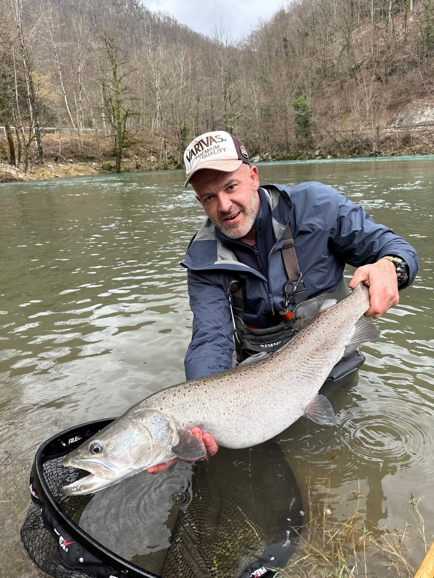 An angler kneeling in the shallows with a trophy huchen