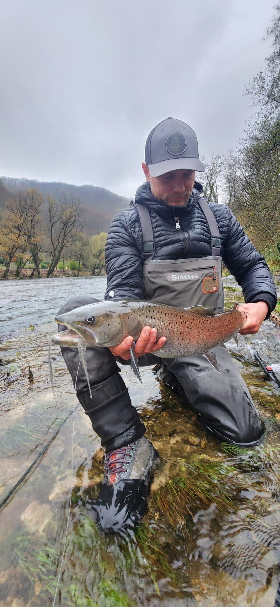 Guide smiling beside a river weir, moments after netting a fish