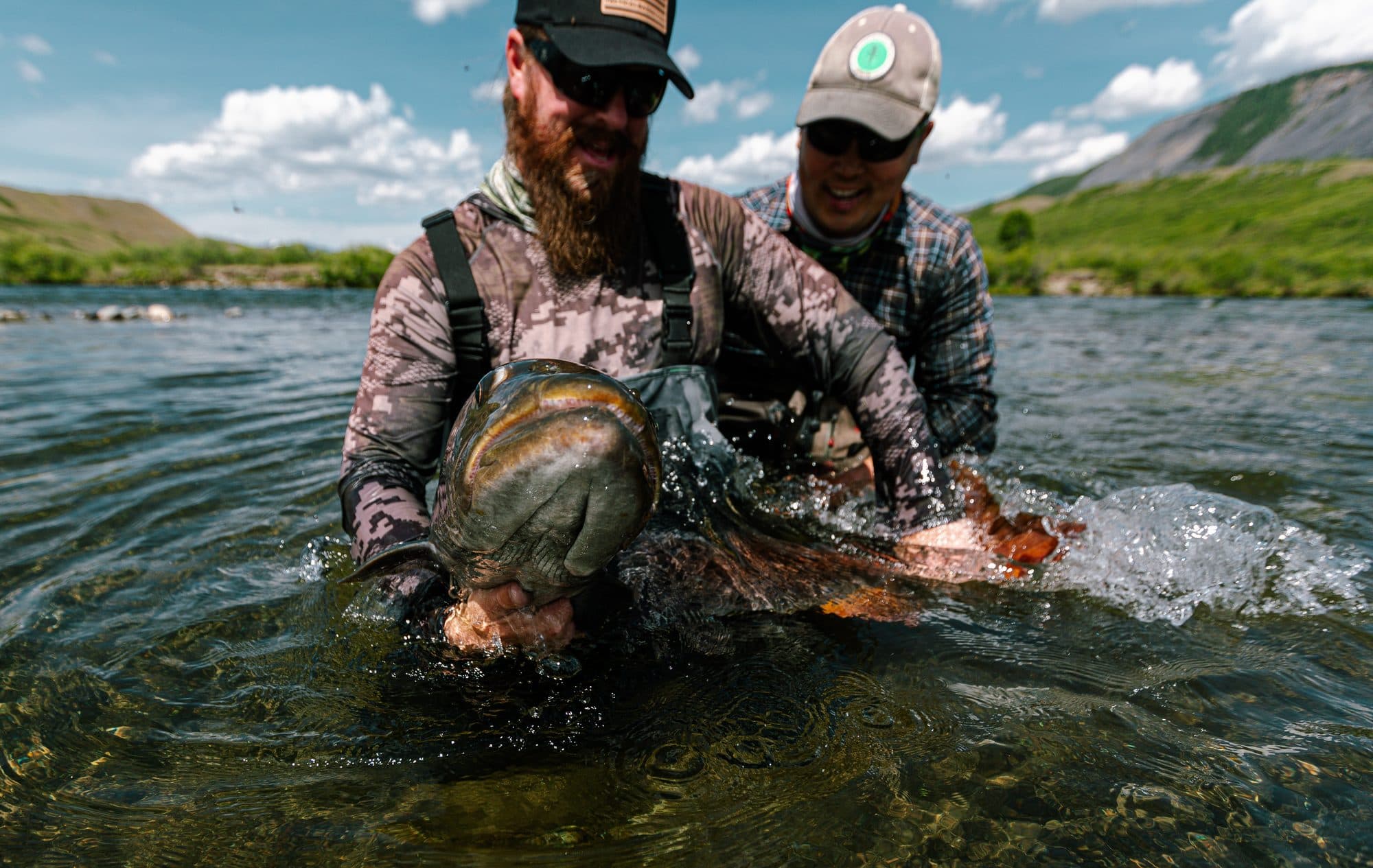 Two anglers together holding a huge taimen
