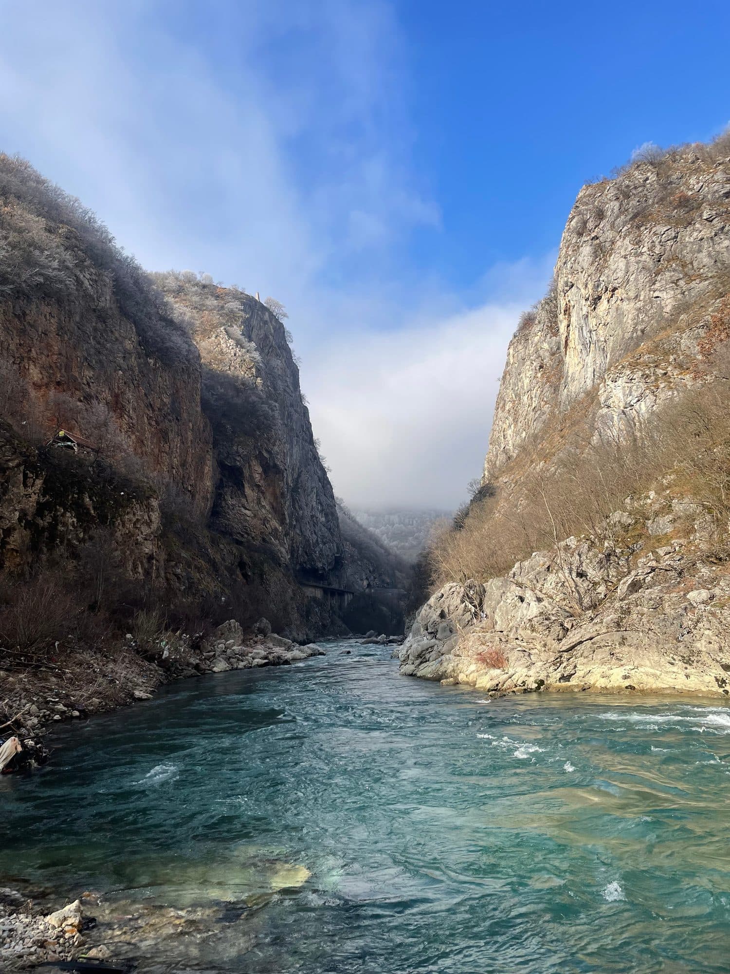 Sheer canyon walls closing in over a green river