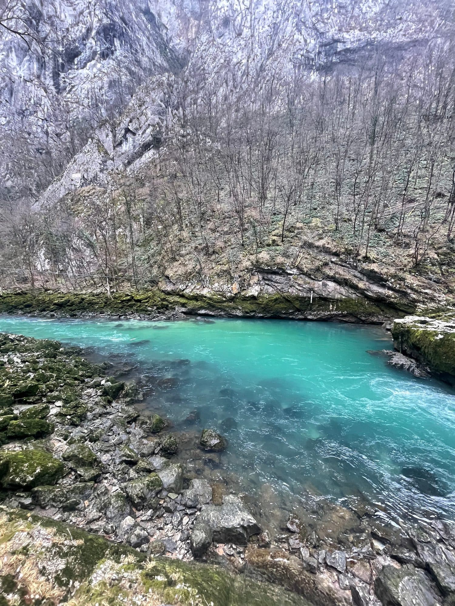 A brilliant turquoise pool held between mossy rocks
